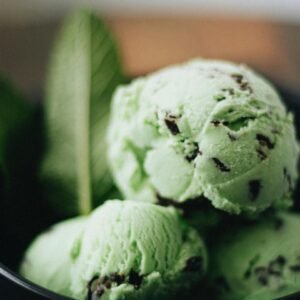 Close-up of artisanal mint chocolate chip ice cream with fresh mint leaves in a bowl.