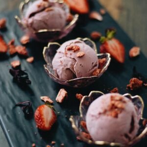 Elegant artisan strawberry ice cream scoops with fresh strawberries and chocolate flakes.