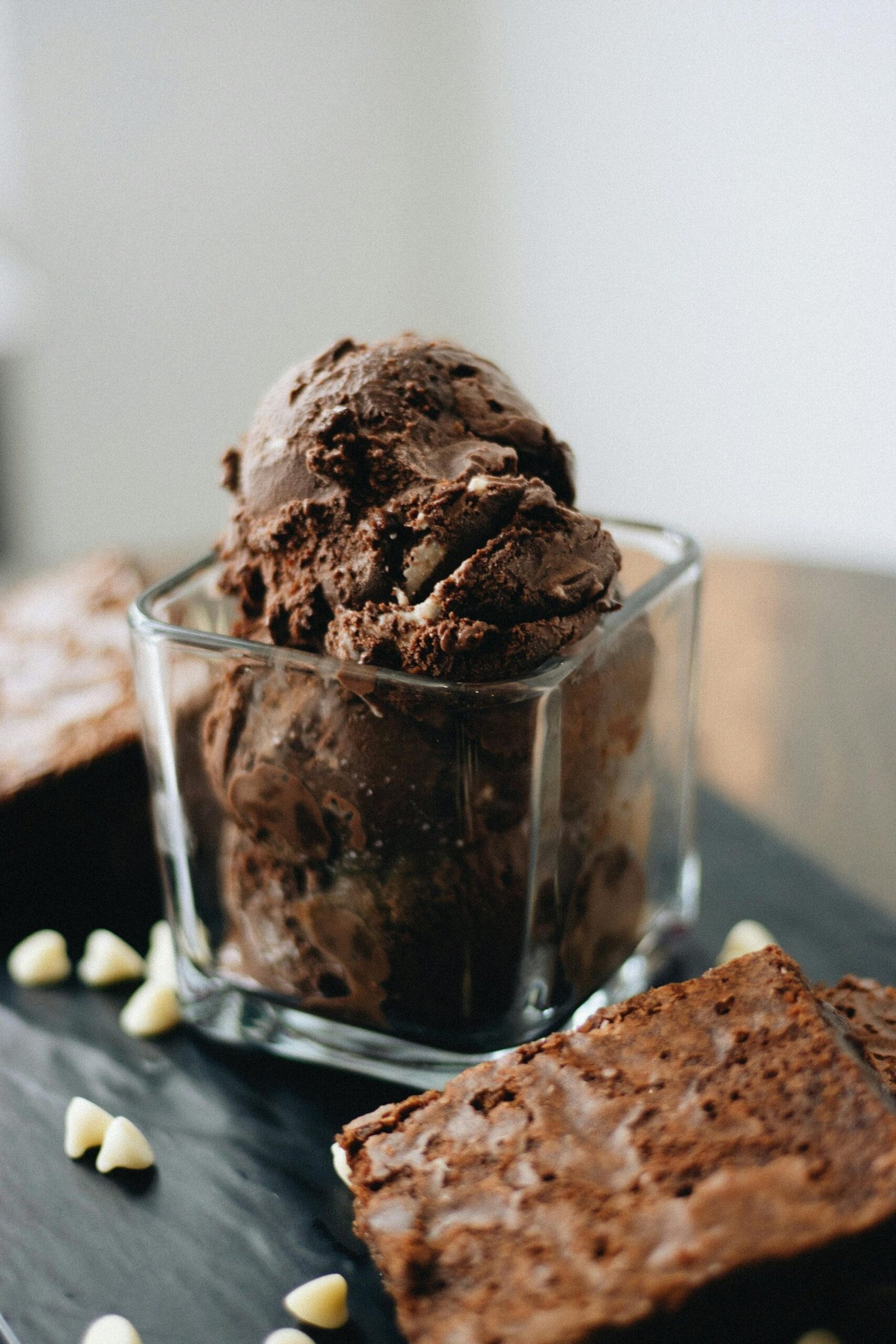 Decadent chocolate ice cream served in a glass with brownie pieces beside it.