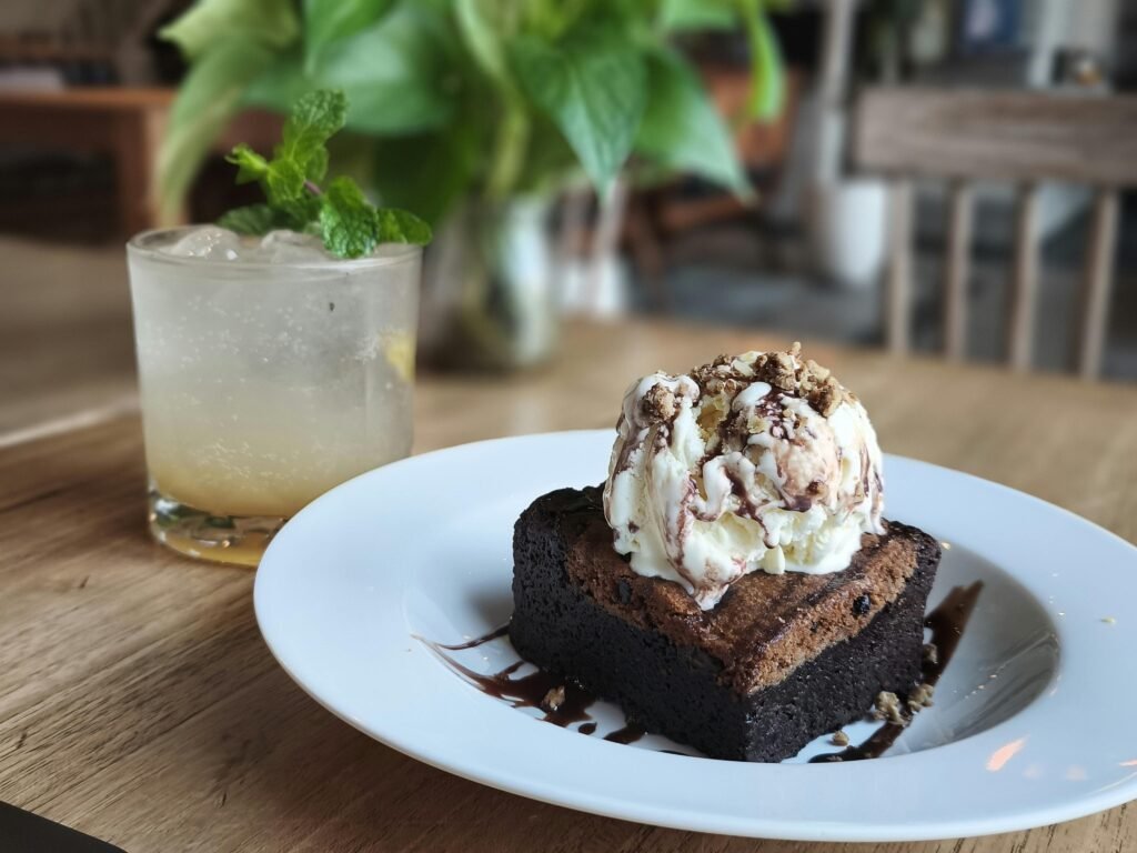 Indulge in a rich brownie sundae paired with a refreshing citrus beverage in a cozy cafe setting.